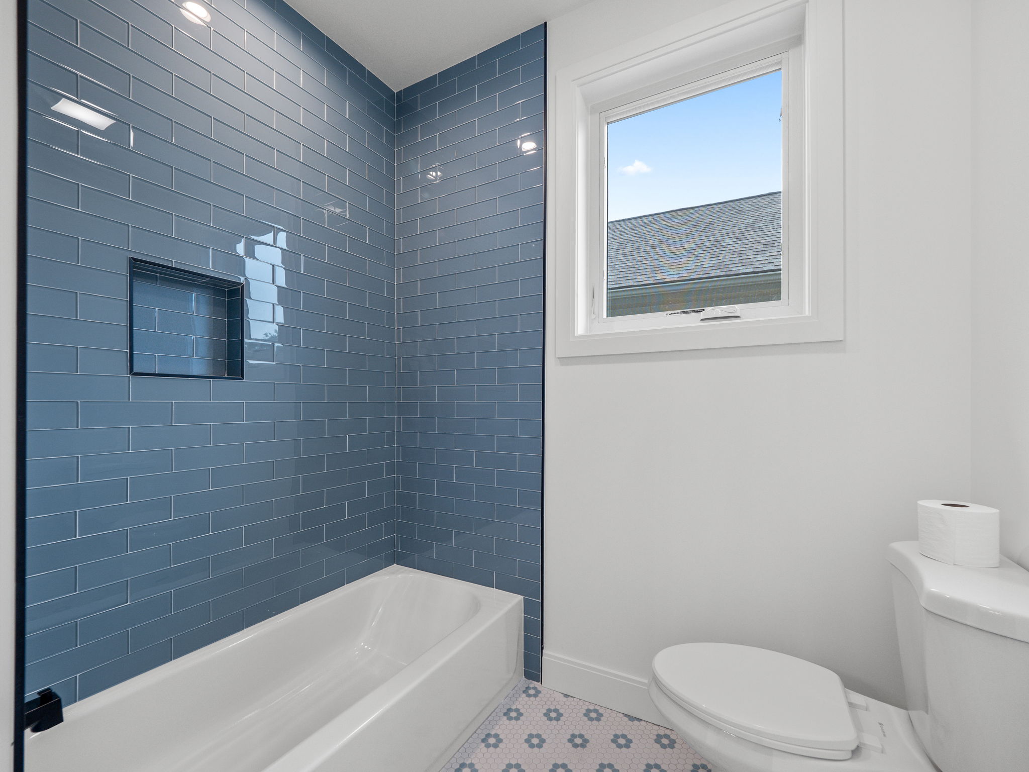 Classic guest bath with blue glass subway tile and patterned floor