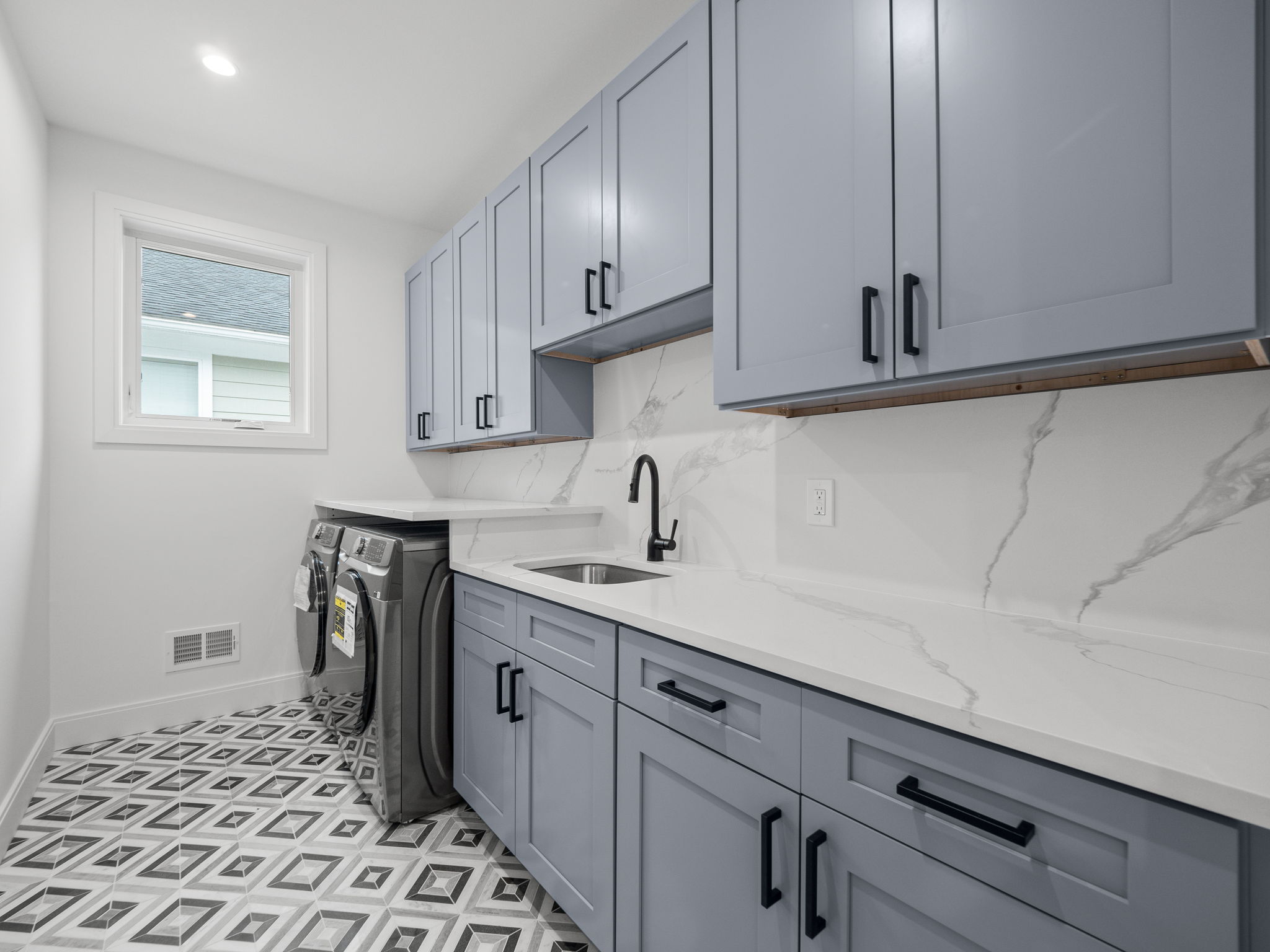 Custom laundry room with periwinkle cabinets and geometric tile