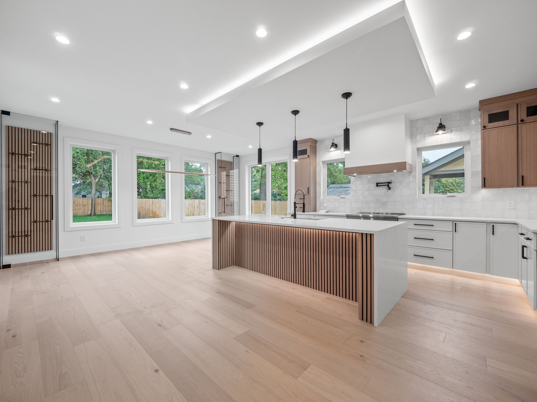 Open great room with floor-to-ceiling windows looking onto landscaped backyard