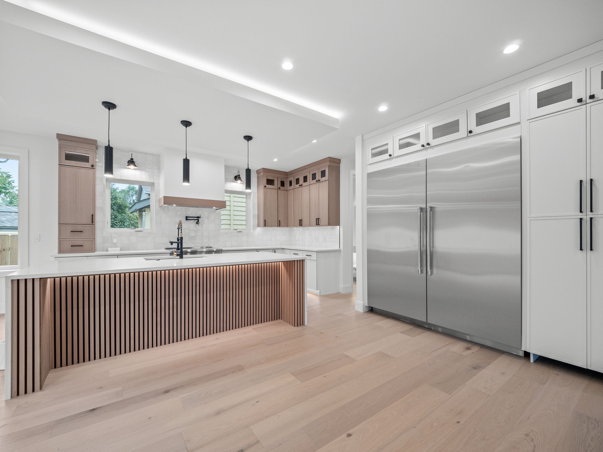 Wide custom kitchen with twin stainless refrigerators and white oak slat island